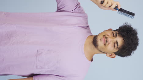 Vertical-video-of-Man-combing-his-hair.